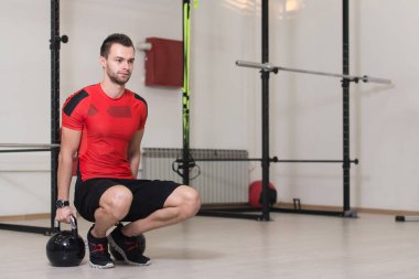 Spor salonunda Kettle Bell 'le antrenman yapan genç adam ağırlık egzersizi yapıyor.
