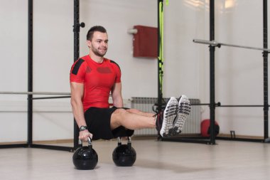 Spor salonunda Kettle Bell 'le antrenman yapan genç adam ağırlık egzersizi yapıyor.
