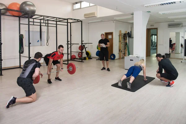 Group of Young Sporting Adults Training on Athletic Field Against Barred Window