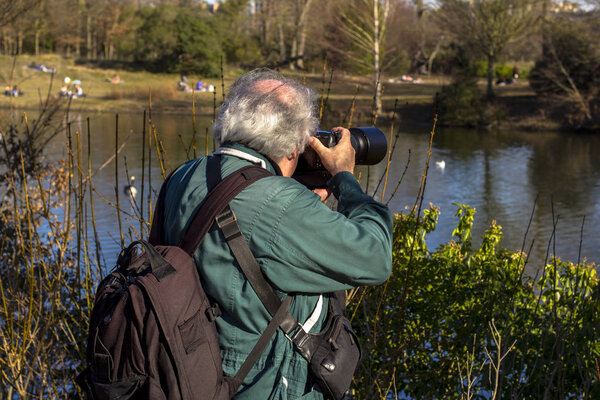 elderly photographer takes pictures of the landscape in the park.