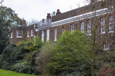 Yeşil çalılar ve ağaçlar arasında büyük bir Avrupa tarzı tuğla bina.