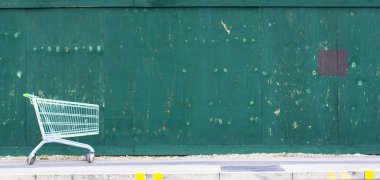 Yeşil çit arka planı. Kaldırımda süpermarket sepetiyanında kopya alanı.