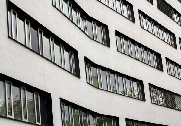 Moderne Fenster in einer Reihe an einem geschwungenen Gebäude. Textur architektonischer Urbanisierung. Straßenfotografie im Stil des Minimalismus. — Stockfoto