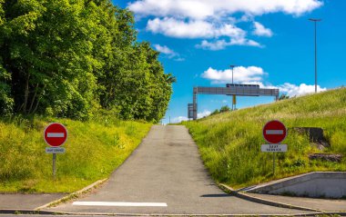 Yol işareti girmeyin. O tarafa giriş yok. Yol yanlış yöne gidiyor. Yeşil ağaçlar ve otoyolun üzerinde mavi gökyüzü.