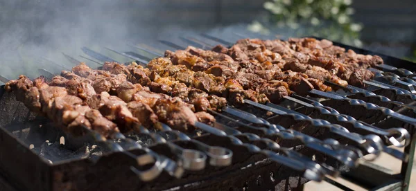 Szaszłyk lub szyszłyk przygotowujący się na grillu nad węglem drzewnym. Grillowane kostki mięsa wieprzowego na metalowym szpikulcu. Mięso na szaszłykach jest pieczone w ogniu — Zdjęcie stockowe