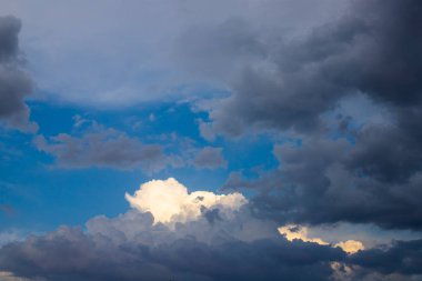Zıt ağır bulutlar aracılığıyla parlak mavi gökyüzü. Fırtınadan sonra güneş bulutların üzerine düşer. Gök gürültülü bulutların ve mavi gökyüzünün parlak kalın dokusu.