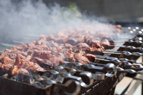 Mięso z dymem na grilla na węgiel drzewny. Grillowane kostki mięsa na szpikulca metalowego. Mięso na szaszłek jest palone w ogniu — Zdjęcie stockowe