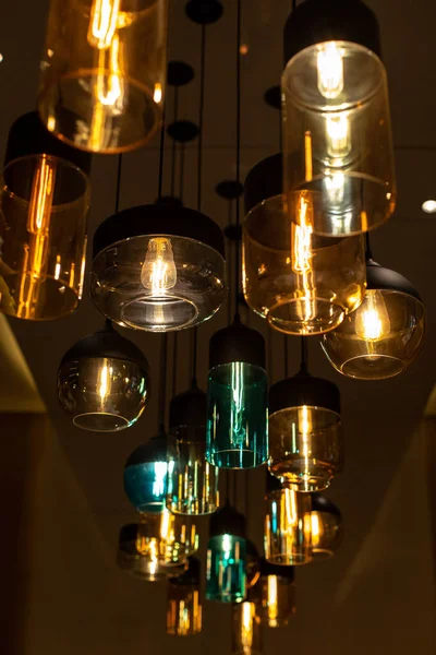 Modern indoor lighting. Beautiful colored glass shades different shapes and sizes. Pleasant warm and cold tones.