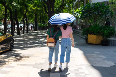 Pekin'in genç kızların gezindiği şık bir bölge. Çinli kızlar güneş ışınlarıkendilerini koruyan bir şemsiye ile yürümek.