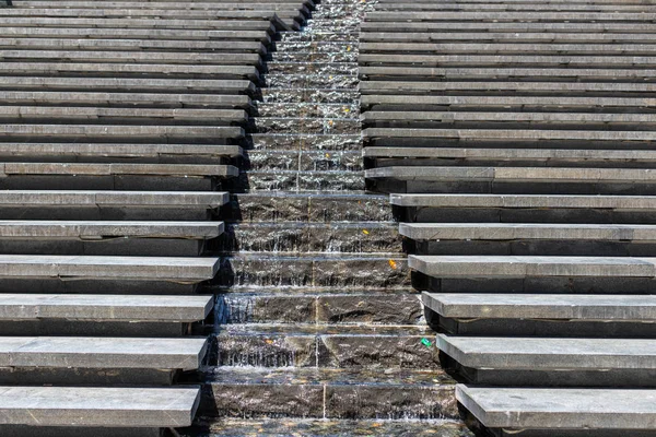 Flusso urbano. Una cascata d'acqua. Scende e nel mezzo, l'acqua scorre lungo i gradini. Passaggi del designer moderno . — Foto Stock