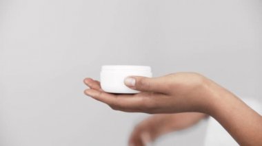 kapsayıcı tutan ve yüz kremi gri izole alarak Afrikalı-Amerikalı kadın kırpılmış görünümü 