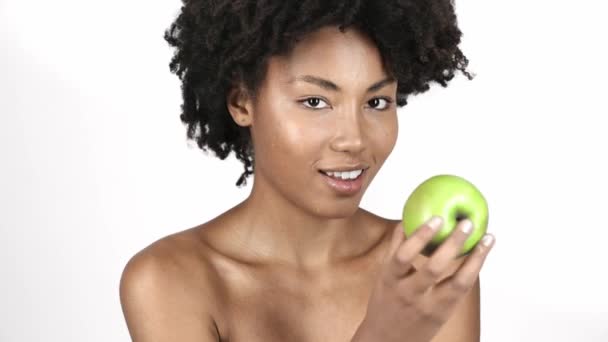 欢快的裸体非洲裔美国女孩看着绿色苹果 吃和笑孤立在白色 — 图库视频影像