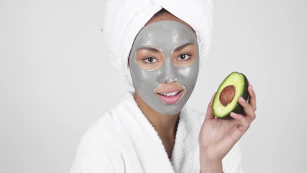 Hermosa Mujer Afroamericana Máscara Arcilla Mirando Aguacate Sonriendo Aislado Gris — Vídeo de stock