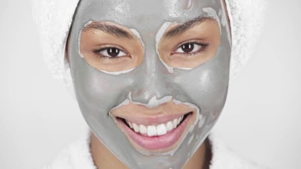 笑みを浮かべて キュウリのスライスと目を覆っていると笑いの分離白粘土マスクで陽気なアフリカ系アメリカ人女性のクローズ アップ — ストック動画