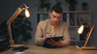 Geceleyin işyerinde ofiste otururken Pano'da yazma yakışıklı, ciddi iş adamı
