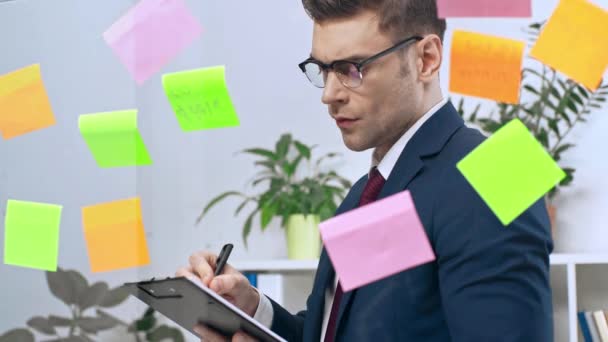 Attentive Businessman Looking Colorful Sticky Notes Writing Clipboard — Stock Video