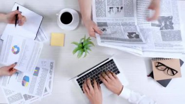 dizüstü bilgisayar kullanarak, belgeleri holding ve not defterinde yazma, gazete okuyan ve kahve içme iş adamları Üstten Görünüm