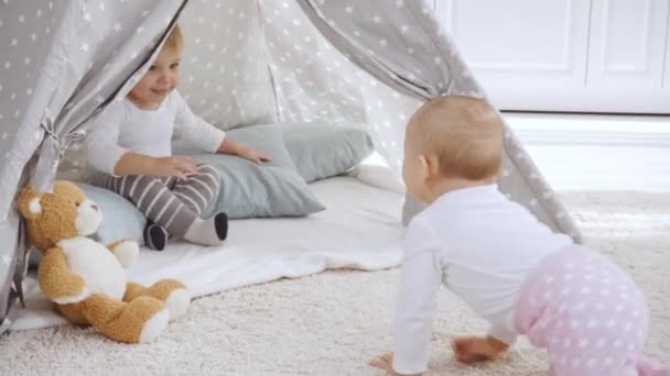 Smiling Toddler Boy Sitting Baby Wigwam While Small Sister Crawling — Stock Video