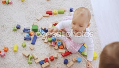 Ahşap çok renkli küpler ile halı oynarken sevimli bebek kardeşi iken oyuncak ayı ile yürüyen Toddler çocuk tepegöz görünümü