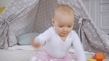 şirin çocuk halı üzerinde oturan ve bebek Wigwam yakın ahşap çok renkli küpler ile oynuyor