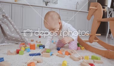 Ahşap çok renkli küpler arasında halı üzerinde tüm fours üzerinde sürünerek sevimli çocuk