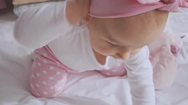 yatakta otururken sevimli gülümseyen çocuk pembe kafa bandı alıyor