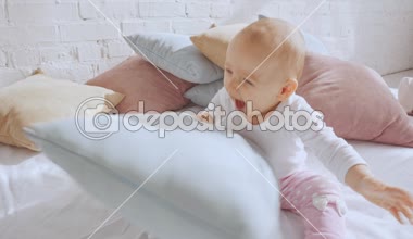 yatakta oturan ve yastıklar ile oynarken sevimli mutlu Toddler çocuk