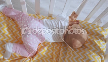  Anne ile oynarken ve sonra yükselen ve etrafına bakarak bebek beşik yatarken gülümseyen çocuk