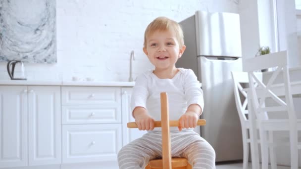 Cute Blonde Toddler Boy Laughing Riding Wooden Rocking Horse Home — Stock Video