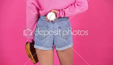 kadının kot şort ve crimson üzerinde izole arkasından topu elinde beyzbol eldiveni ile kırpılmış görünümü