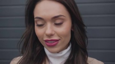 ceplerinde soğuk rüzgarlı havalarda eller ile bej trençkot poz içinde gülümseyen zarif kadın