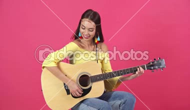 stüdyo çekimi akustik gitar üzerinde crimson izole çalmaya mutlu genç kadın