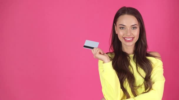 工作室拍摄有吸引力的微笑的年轻女子拿着信用卡在深红色背景 — 图库视频影像