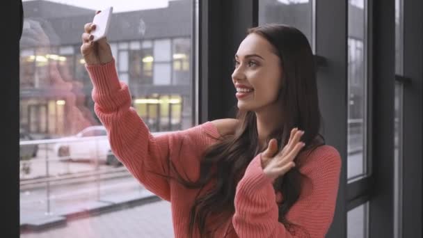 Vackra Leende Ung Kvinna Stående Nära Fönstret Och Videochatt Smartphone — Stockvideo