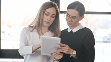 Dijital tablet kullanarak çekici iş arkadaşları, konuşan ve ofiste gülümsüyor 