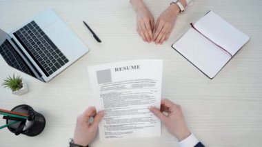 adam üst görünümü kadın kalem alarak ve ofis dizüstü yakın CV ve sallayarak eller yakın tutarak devam veren 