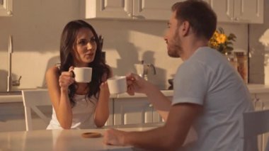 neşeli esmer kadın bardak tutan, erkekle konuşurken, gesturing, kahve içme ve mutfakta gülüyor 