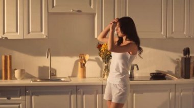 esmer kadın kızartma tavası yanında duran, gülümseyen, ve mutfakta dans 