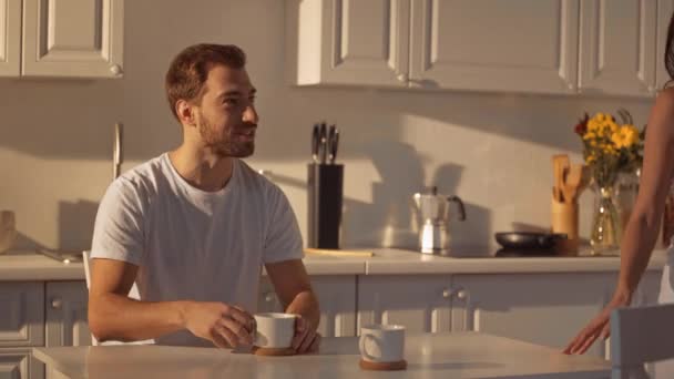 Брюнетка Женщина Глядя Мужчину Давая Чашку Мужчина Пить Кофе Улыбаясь — стоковое видео