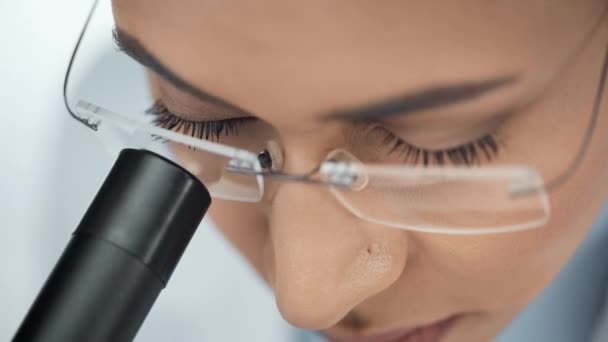 顕微鏡を用いて眼鏡で集中したアフリカ系アメリカ人科学者のクローズアップビュー — ストック動画