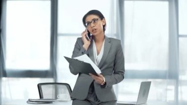 masanın yanında duran gözlüklü, pano tutan ve akıllı telefonda konuşan afrikalı-amerikalı iş kadını gülümseyen