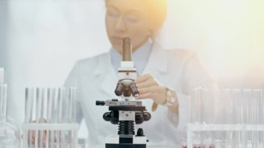 Gözlüklü Afrikalı Amerikalı bilim adamı laboratuvarda mikroskop kullanıyor. 