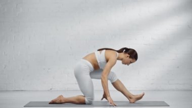 Kadın, Ashwa Sanchalanasana çalışırken esniyor, sicim yapıyor, eka pada rajakapo hanumanasana yapıyor ve namaste işareti gösteriyor.