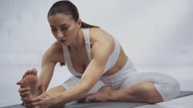 yoga mat üzerinde janu sirsasana pratik ederken germe odaklanmış kadın