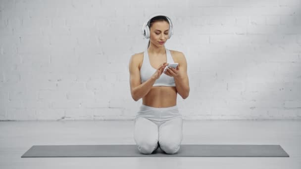 Vrouw Hoofdtelefoon Scrollen Smartphone Scherm Luisteren Muziek Met Glimlach Stretching — Stockvideo