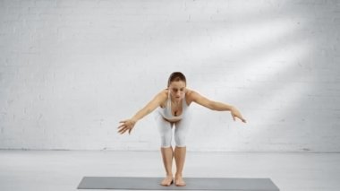 yalınayak kadın eka pada koundinyasana pratik ve namaste işareti gösteren