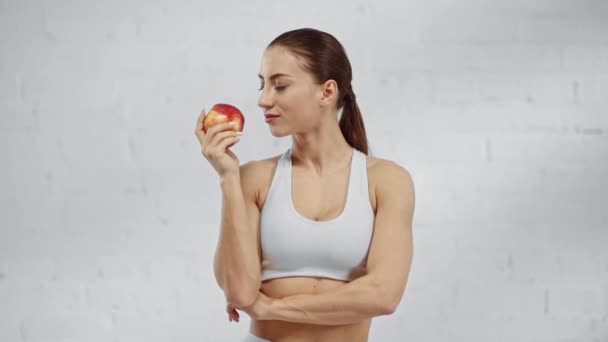 かわいい女性がリンゴを嗅ぎ 噛んで笑顔でカメラを見ている — ストック動画
