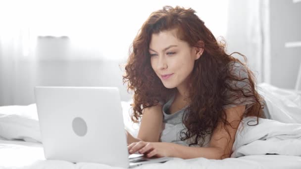 Piękna Dziewczyna Leżącego Łóżku Wpisując Laptopie Uśmiechając Się Patrząc Aparat — Wideo stockowe