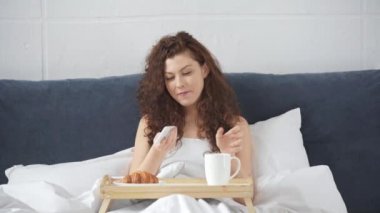 akıllı telefon kullanarak güzel kız, kahve içme ve yatakta gülümseyen