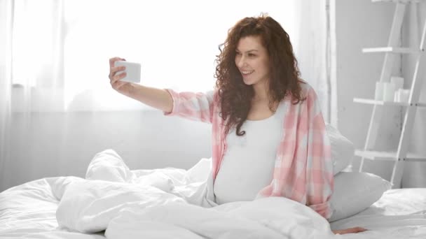 Zwangere Jonge Vrouw Met Video Chat Smartphone Zwaaien Glimlachend Bed — Stockvideo